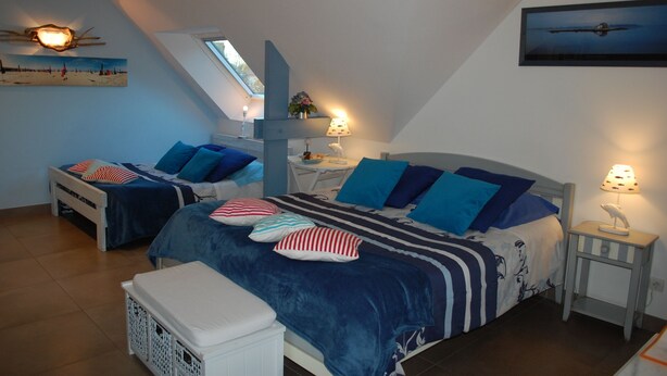 A bedroom with two beds, a skylight, a nightstand with a lamp, and a painting on the wall. - Le Clos des pommiers (Tracy-sur-Mer)