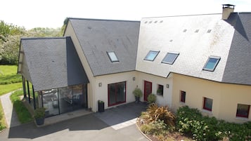 Een modern huis met twee verdiepingen, een schuin dak, grote glasramen en een verzorgde tuin.