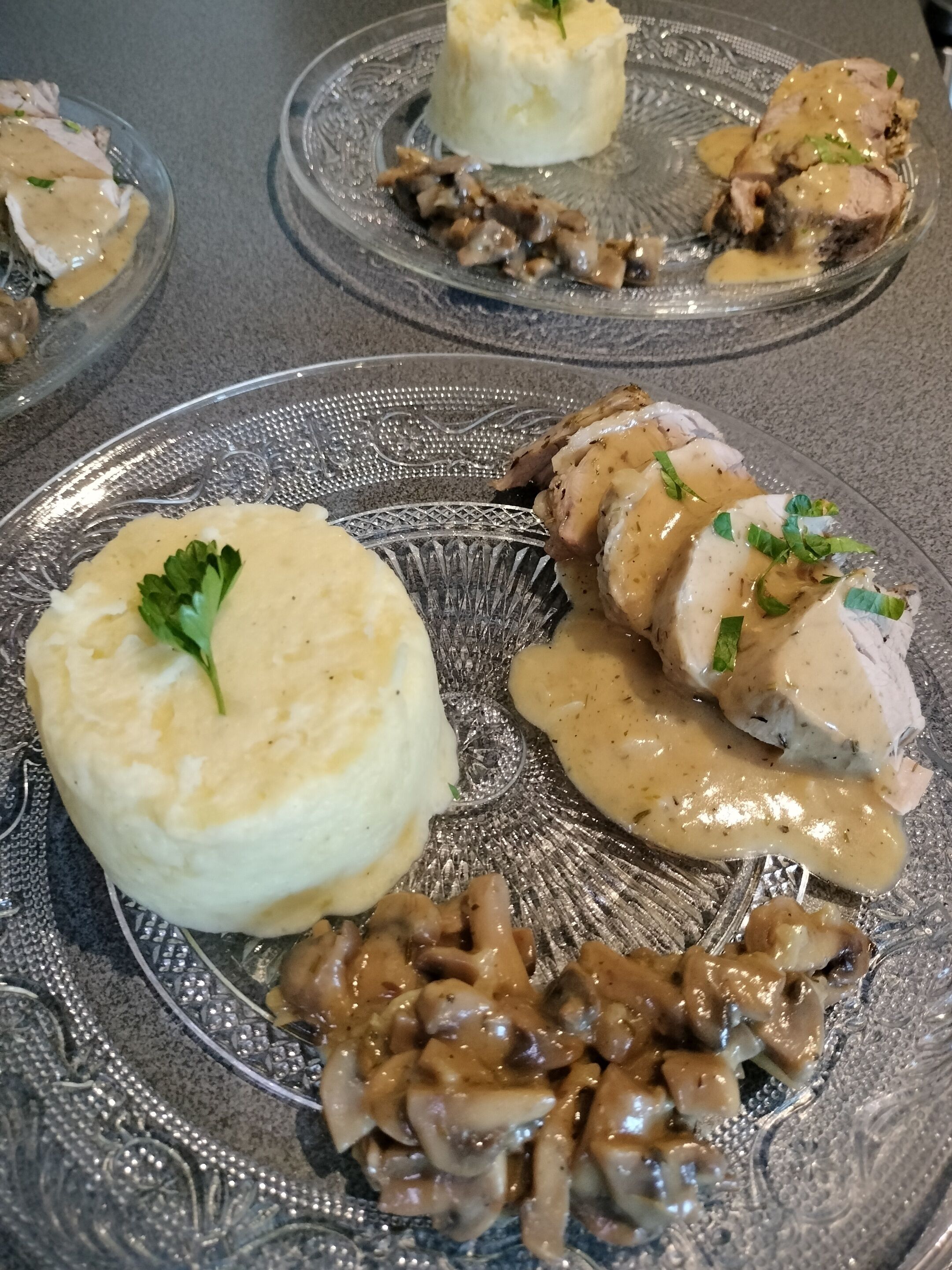 Un plato con carne en rodajas, puré de papas y salsa de champiñones.