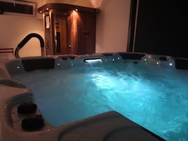 Un jacuzzi con múltiples chorros, una puerta de madera y un ventanal pequeño.