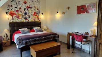 Un dormitorio con una cama grande, un banco de madera, un escritorio con una silla y una pared decorada con motivos florales.