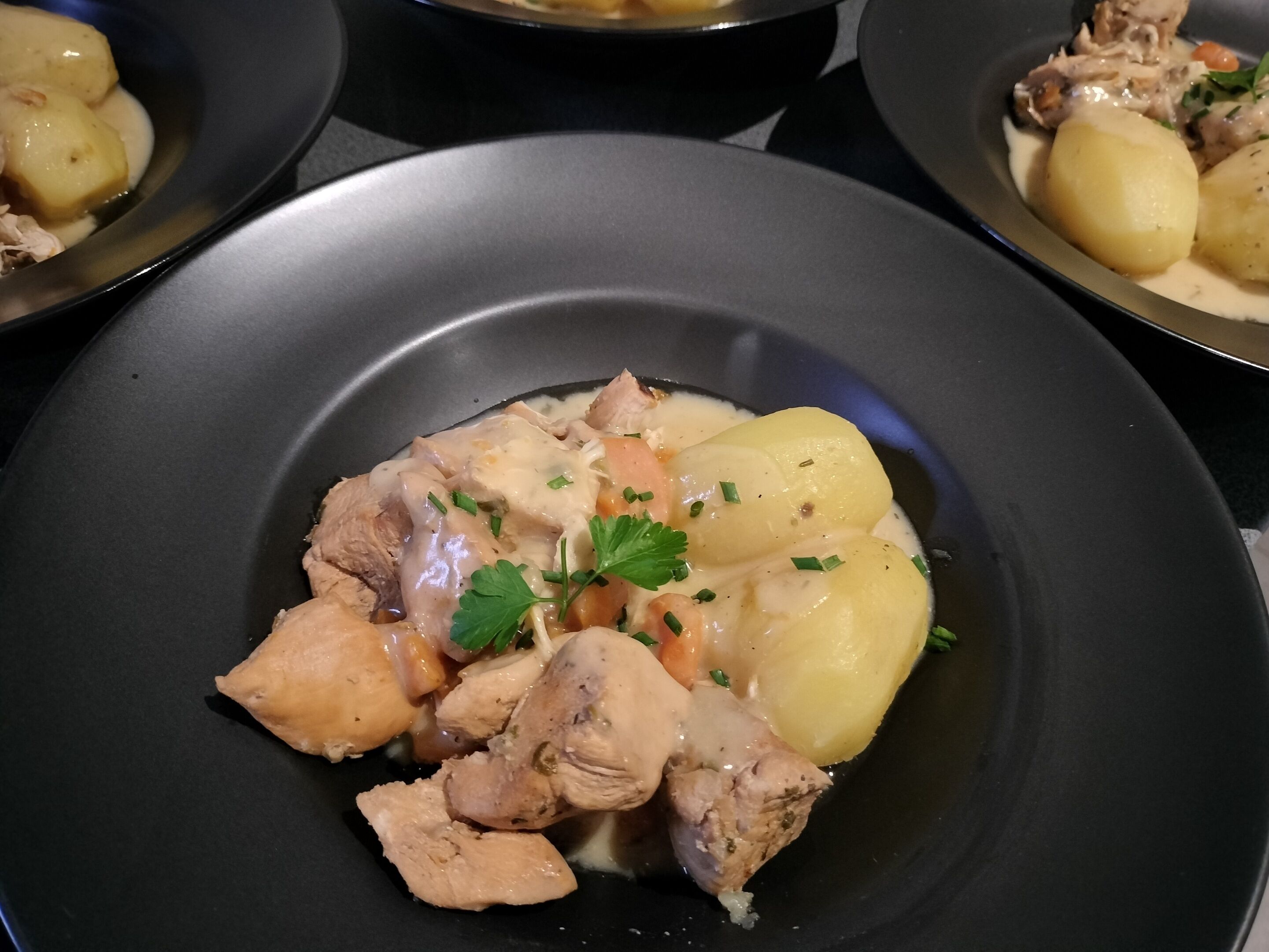 Een bord eten met kip, aardappelen en wortelen.