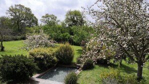 A garden with a pond, a wooden pathway, and various flowering plants. - Le Clos des pommiers (Tracy-sur-Mer)