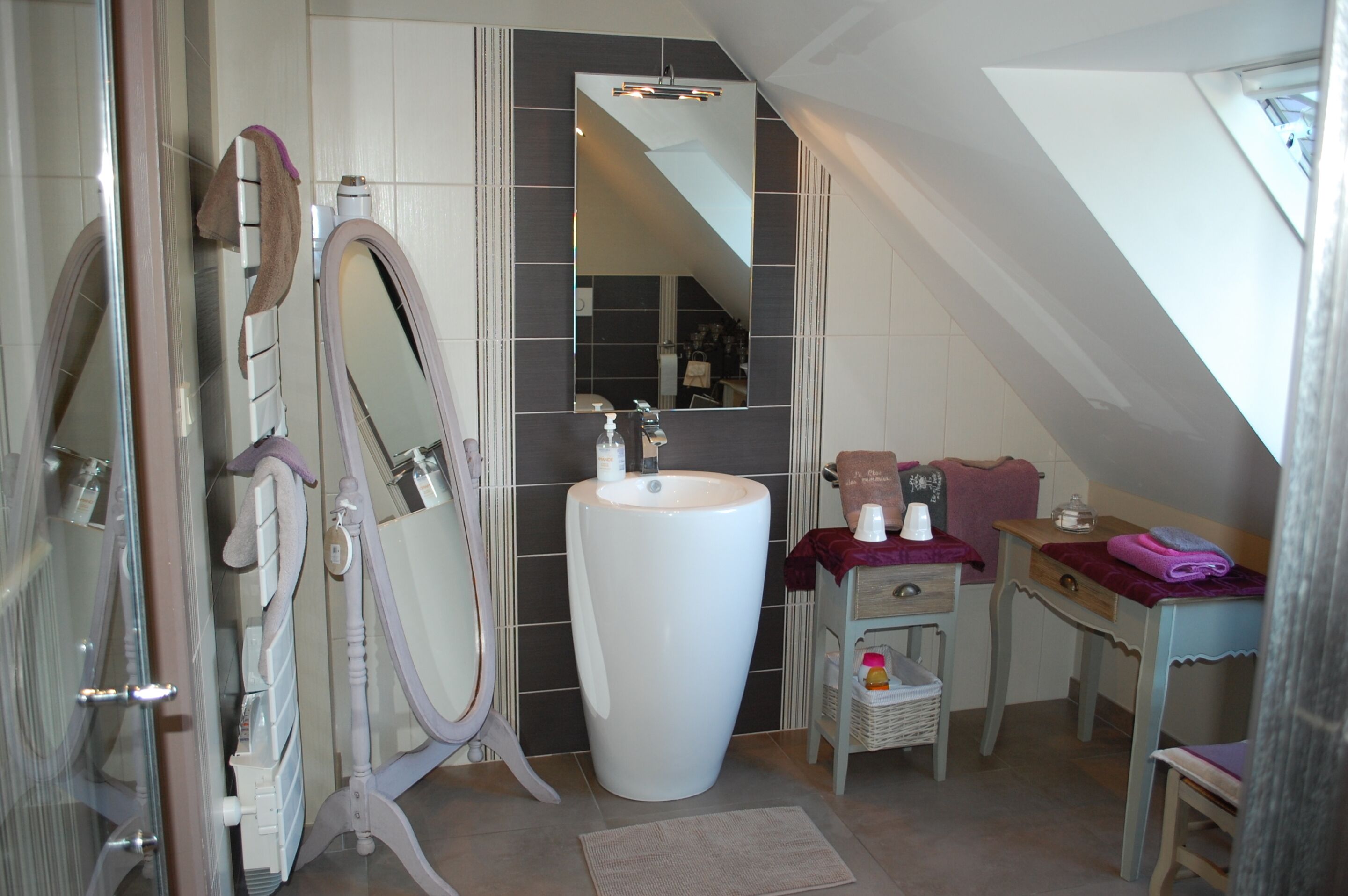 Een badkamer met een grote spiegel, een wastafel en een badkamermeubel met handdoekhouder.