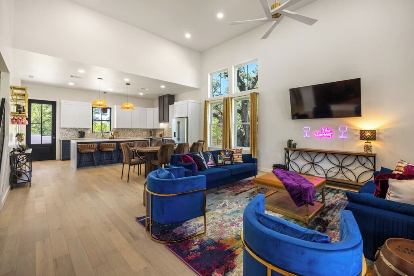 A spacious living area with a blue sofa set, a coffee table, and a TV mounted on the wall.