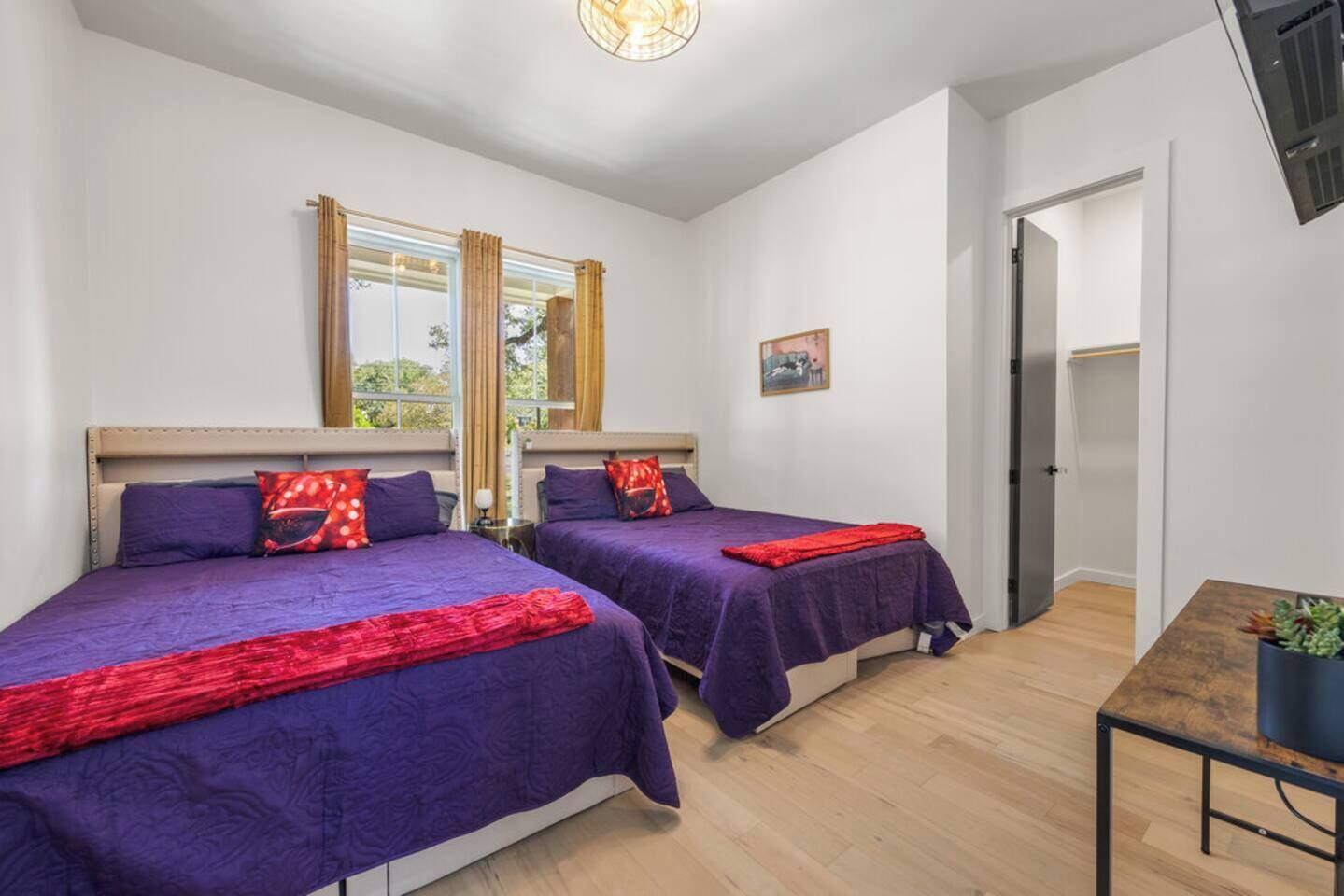 Une chambre avec deux lits, une petite table et une fenêtre avec des rideaux.