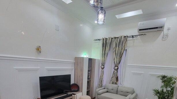 A modern living room with a flat-screen TV, a sofa, a dining table with chairs, and a patterned rug. - 3 minutes from MAYA-MAYA (batignole) airport, secure residential area. (Moungali)