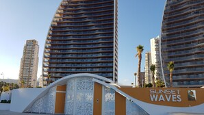Un bâtiment moderne avec une entrée incurvée et le nom « Sunset Waves » inscrit sur la façade.