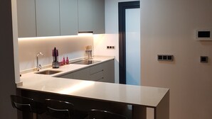 Une cuisine moderne dotée d’un îlot central, de tabourets de bar et d’appareils électroménagers intégrés.
