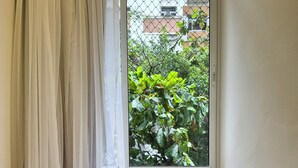 A dining table set with plates, glasses, and cutlery, positioned near a window with a view of greenery and buildings. - 2 quartos à 400m praia de Copacabana (Rio de Janeiro)