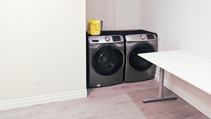 A laundry room with two front-loading washing machines and a yellow detergent bottle on a shelf. - Newly renovated stylish 3B3B basement suite with full kitchen (Richmond Hill)