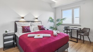 Ein modernes Hotelzimmer mit einem großen Bett, Nachttischen, einem Schreibtisch und Stühlen.