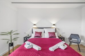 Een hotelkamer met een groot bed, twee nachtkastjes, een potplant en een stoel.