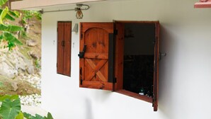 Quarto com parede branca, porta de madeira e janela com persiana de madeira.