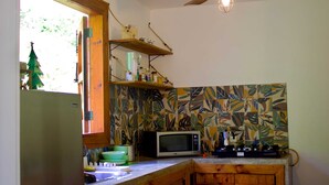 Uma cozinha com armário de madeira, micro-ondas e ventilador de teto.