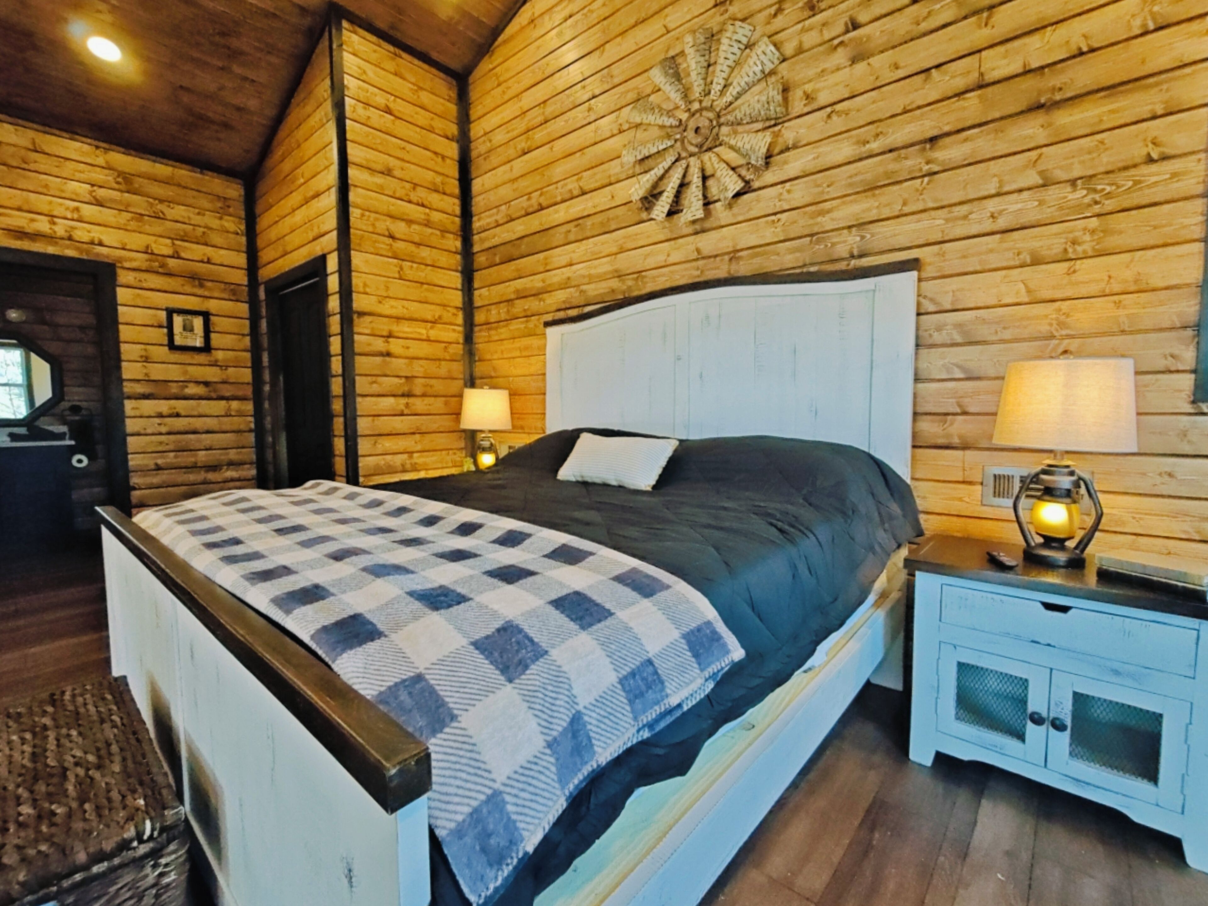 A wooden cabin-style bedroom with a bed, nightstands, and a decorative wall piece.