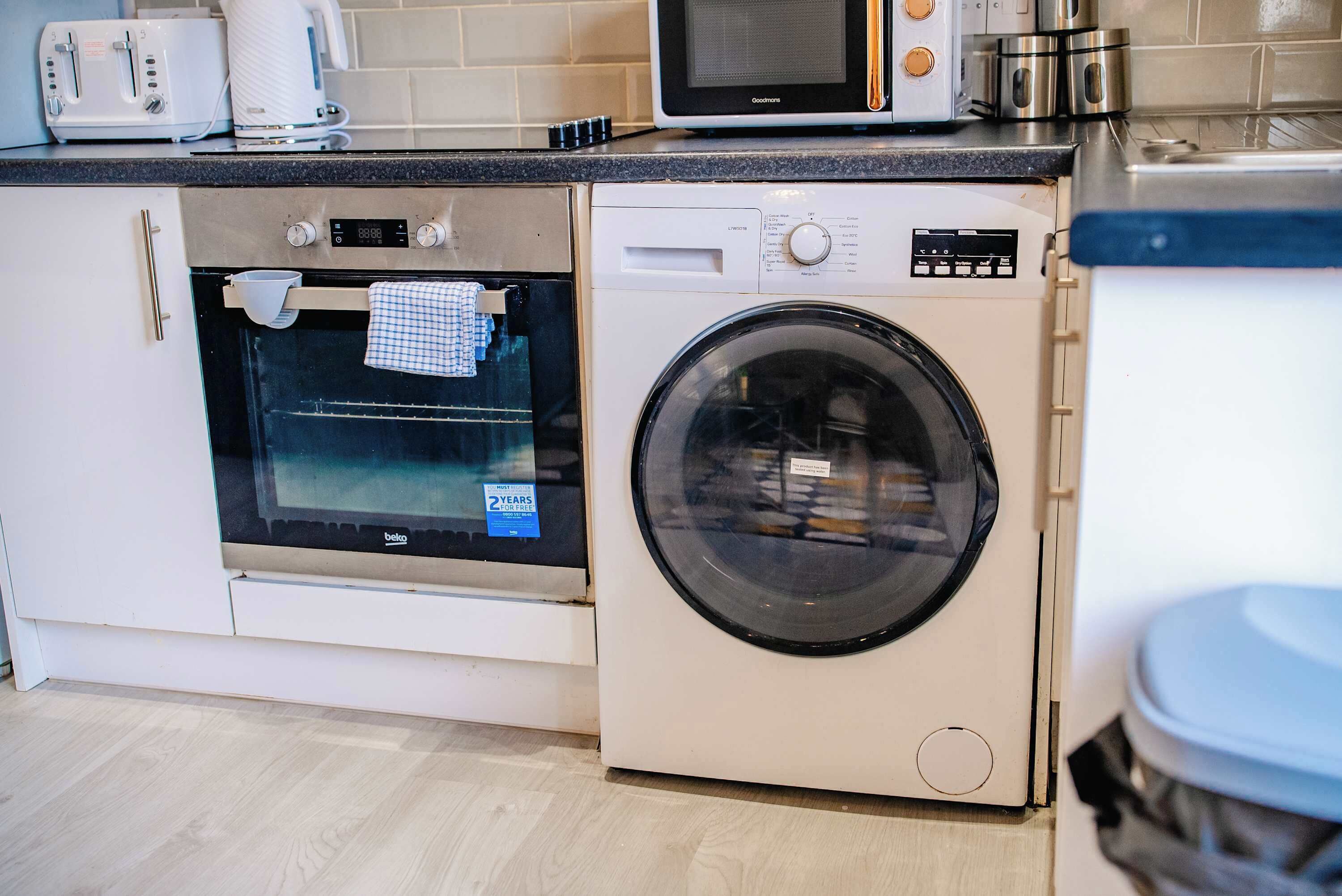 A kitchen with a built-in oven, microwave, and a front-loading washing machine.