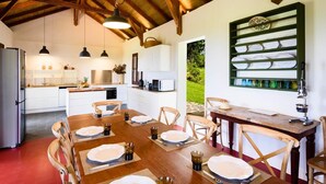Una cocina amplia con vigas de madera, muebles blancos y una zona de comedor preparada para seis comensales.