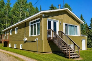 A two-story lodge with a wooden exterior, a staircase, and a deck.