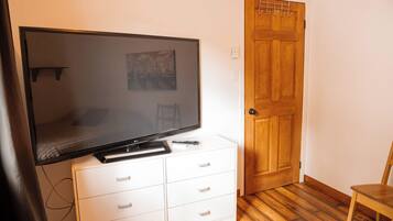 Een kamer met een televisie op een kast, een houten deur en een stoel.