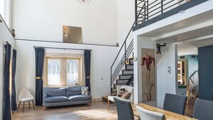 A spacious living area with a staircase, a dining table, and a sofa. - L'Ecomaison - Luminous & Open Space (Rouyn-Noranda)