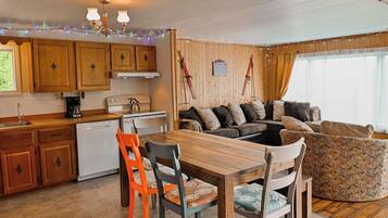 A cozy kitchen with wooden cabinets, a dining table, and a sofa.