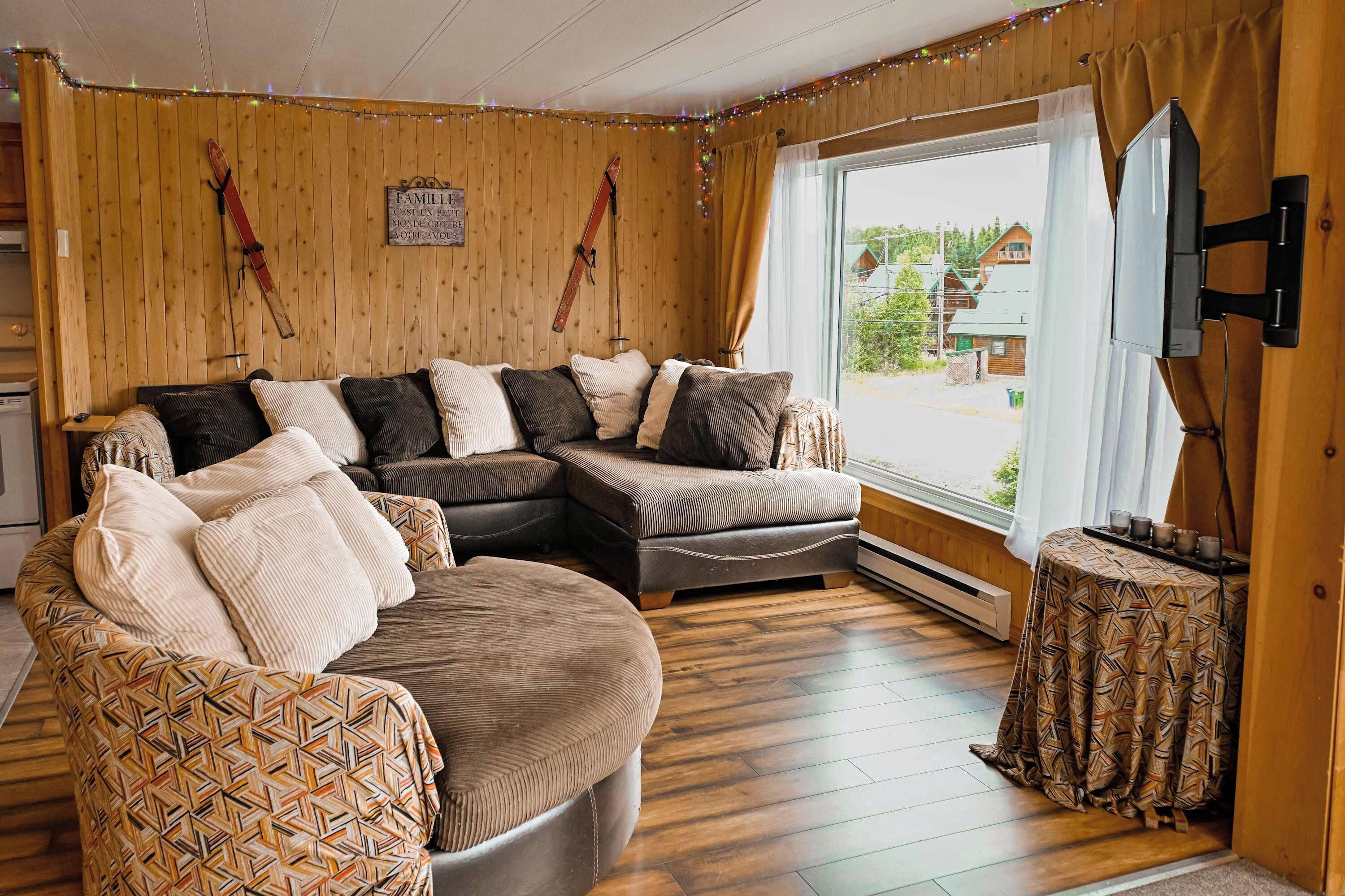A cozy living room with a sectional sofa, a patterned armchair, and a small table with cups.