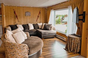 A cozy living room with a sectional sofa, a patterned armchair, and a small table with cups. - Double House - Mont-Video (Barraute)
