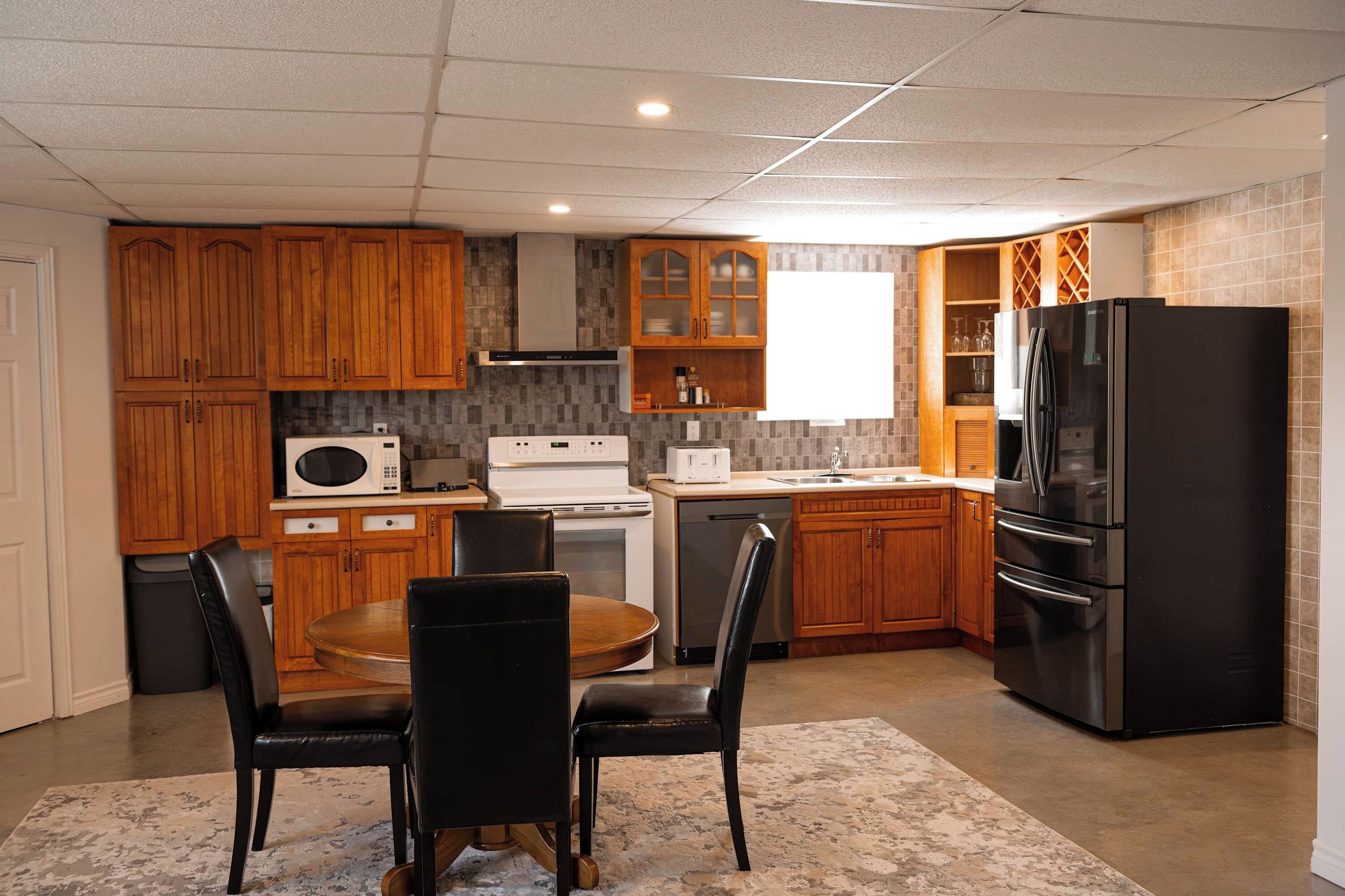 A modern kitchen with wooden cabinets, a stainless steel refrigerator, a microwave, and a dishwasher.