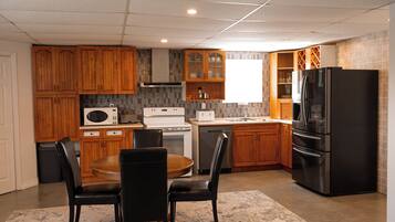 A modern kitchen with wooden cabinets, a stainless steel refrigerator, a microwave, and a dishwasher.