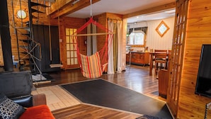 Un interior de madera con una hamaca, una chimenea y un comedor.