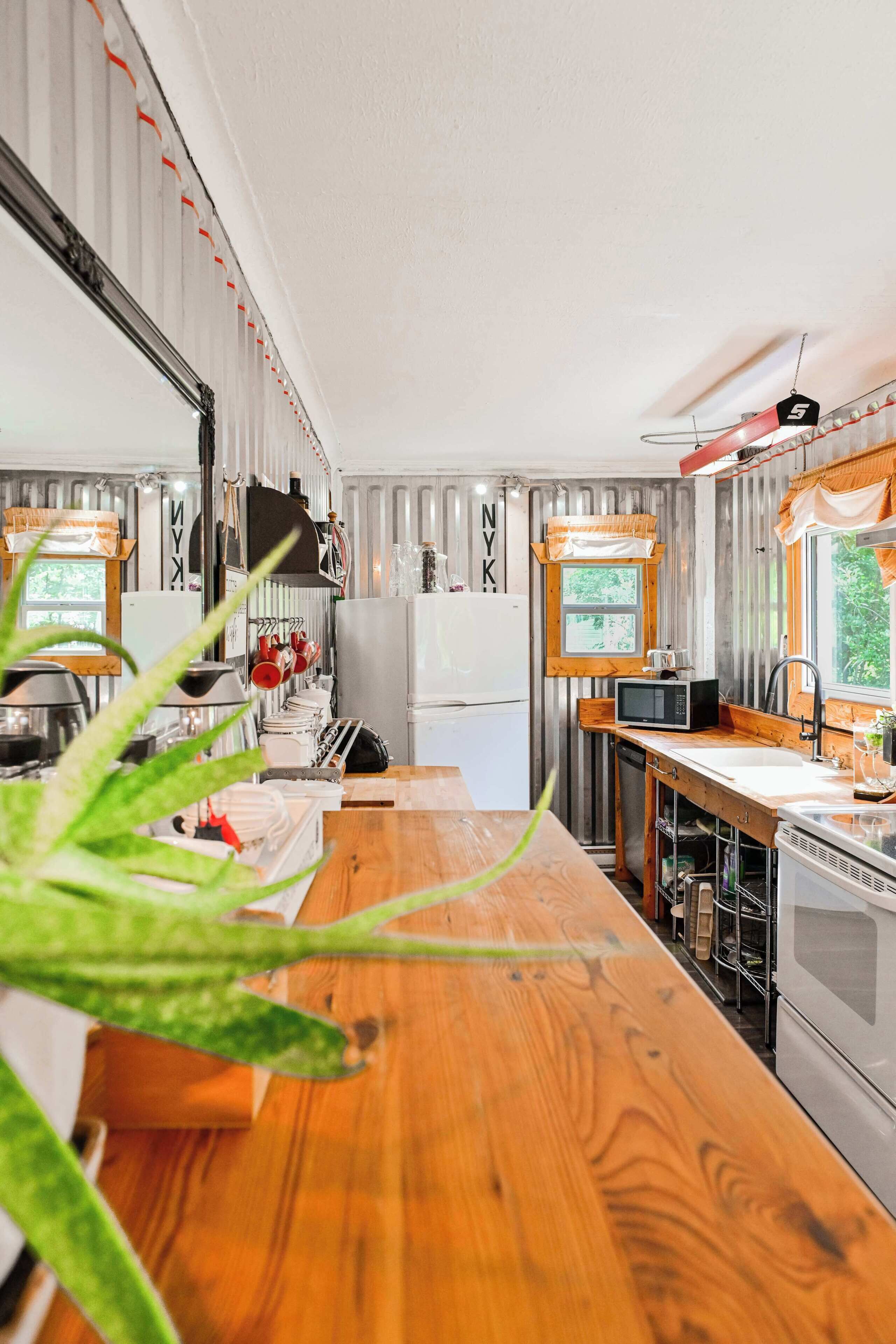 A compact kitchen with a wooden countertop, a refrigerator, a microwave, and a sink.