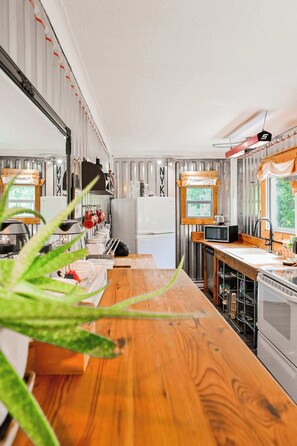 A compact kitchen with a wooden countertop, a refrigerator, a microwave, and a sink. - Maison Conteneur d'Expedition (Amos)