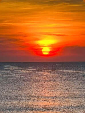 A sunset over the ocean with a person standing on the beach. - Beach House: Turtle’s Cove #3-Full Kitchen, Washer and Dryer, 1st Floor (Melbourne Beach)