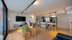 Un salon moderne doté d’un grand téléviseur, d’un coin repas et d’une cuisine.