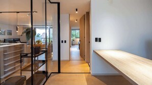 Un intérieur moderne avec un comptoir d’accueil en bois, une cloison en verre et un couloir menant à un espace de vie.