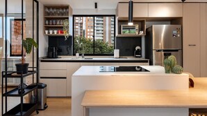 Une cuisine moderne dotée d’un îlot central, d’appareils électroménagers intégrés et offrant une vue sur la ville.