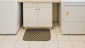 Ein kleiner Hauswirtschaftsraum mit Spüle, zwei Waschmaschinen und einer Deckenleuchte.