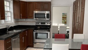Eine moderne Küche mit Edelstahlgeräten, Holzschränken und einem Essbereich mit Glastisch und Stühlen.