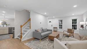 Un salon spacieux avec un canapé gris, une table basse en bois et un escalier doté de rampes en bois.
