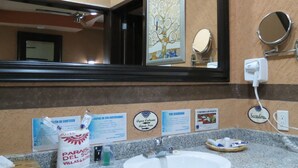 A hotel bathroom with a granite countertop, a sink, a mirror, and various toiletries. - Habitación doble en Paraíso del Sur (Cuernavaca)