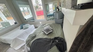 A bedroom with a bed, a small table, and a window.
