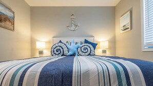 A bed with striped bedding, two decorative pillows, a wall-mounted anchor, and two wall-mounted lamps. - Leaning Palm/Canal home/boat ramp & dock/game room + fire pit & lanai/sleeps 9 (Port Charlotte)
