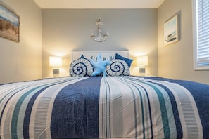 A bed with striped bedding, two decorative pillows, a wall-mounted anchor, and two wall-mounted lamps. - Leaning Palm/Canal home/boat ramp & dock/game room + fire pit & lanai/sleeps 9 (Port Charlotte)