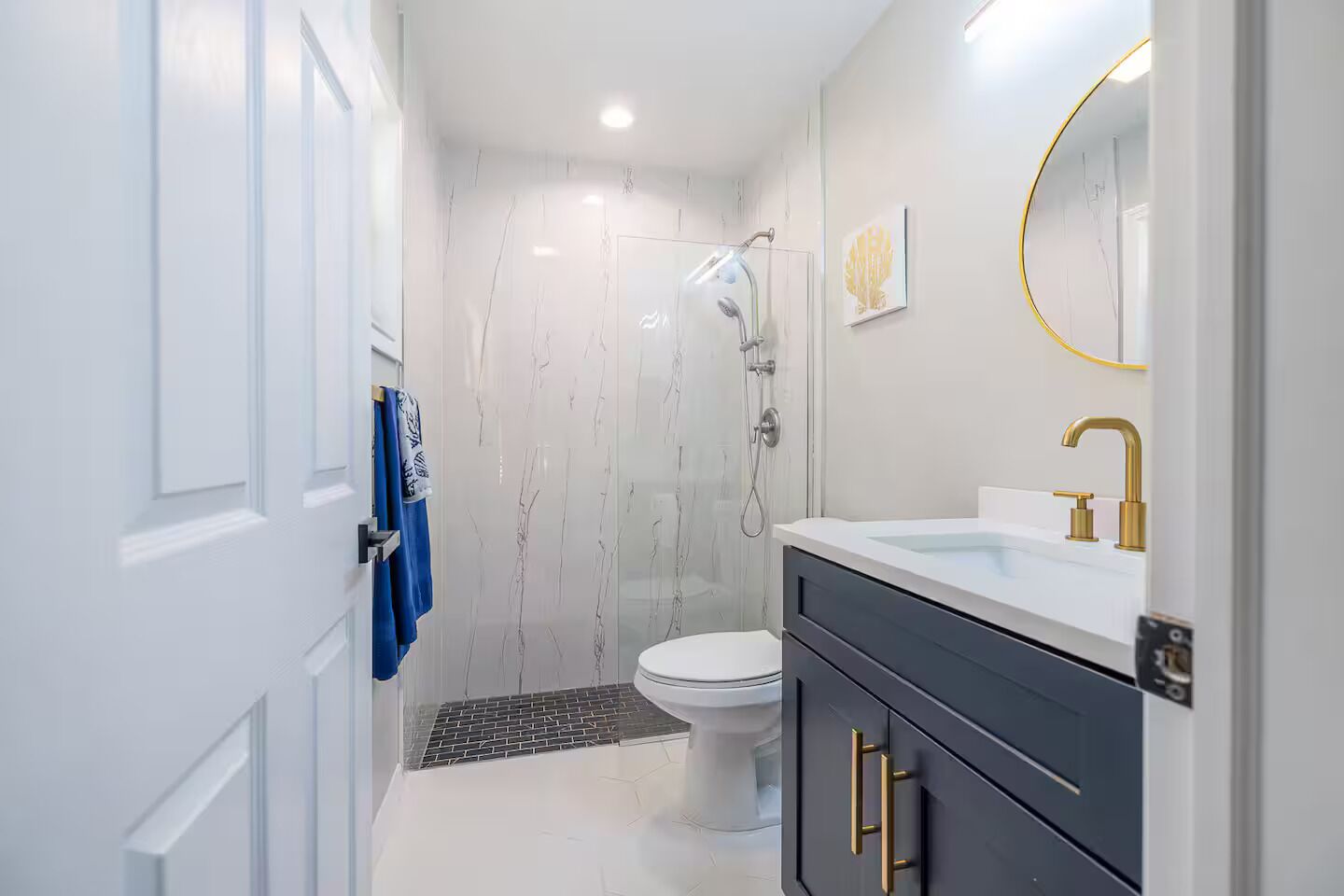 Een moderne badkamer met toilet, douche en wastafel met gouden kraan.