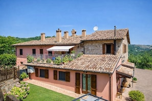 A two-story house with a tiled roof, a balcony, and a satellite dish. - Villa Angolo Fiorito (Marche)