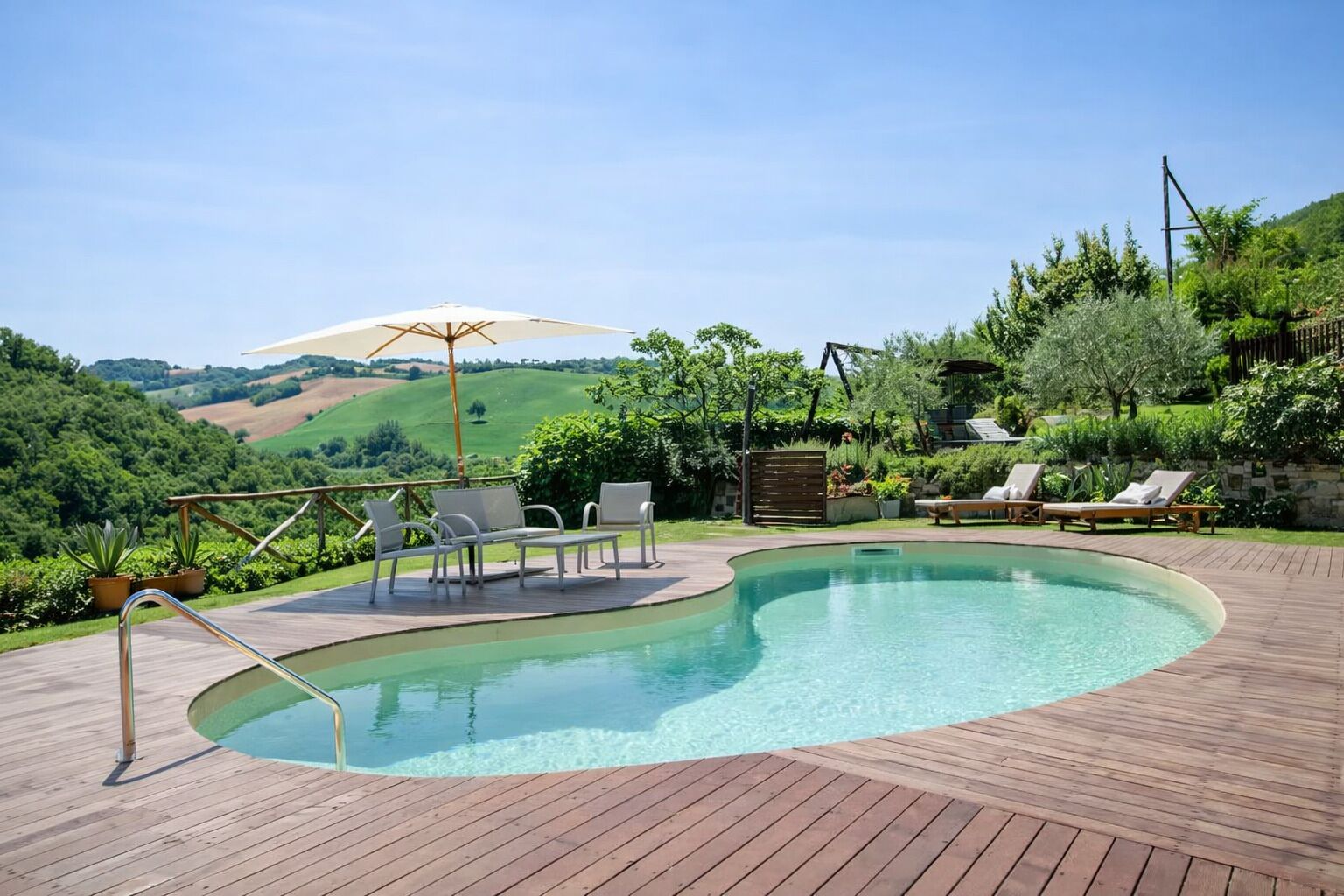 Un patio in legno con piscina, poltrona a sdraio e ombrellone.
