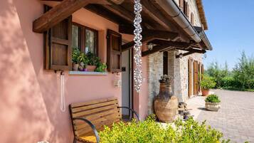 Un edificio rustico con travi in legno, una panchina e piante in vaso.
