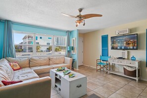 A living room with a sofa, coffee table, and a television. - Deja Blue: Navarre Beach (Navarre)