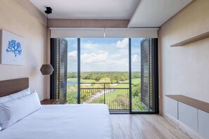 Een slaapkamer met een groot bed, uitzicht op een landschap door open luiken en een plafondlamp.